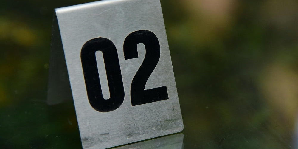 numéro 02 sur plaque métallique argentée symbolisant l'heure miroir 02h02 et la patience