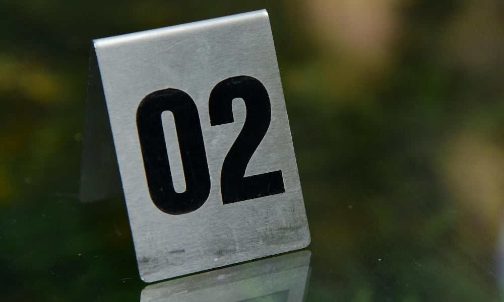 numéro 02 sur plaque métallique argentée symbolisant l'heure miroir 02h02 et la patience