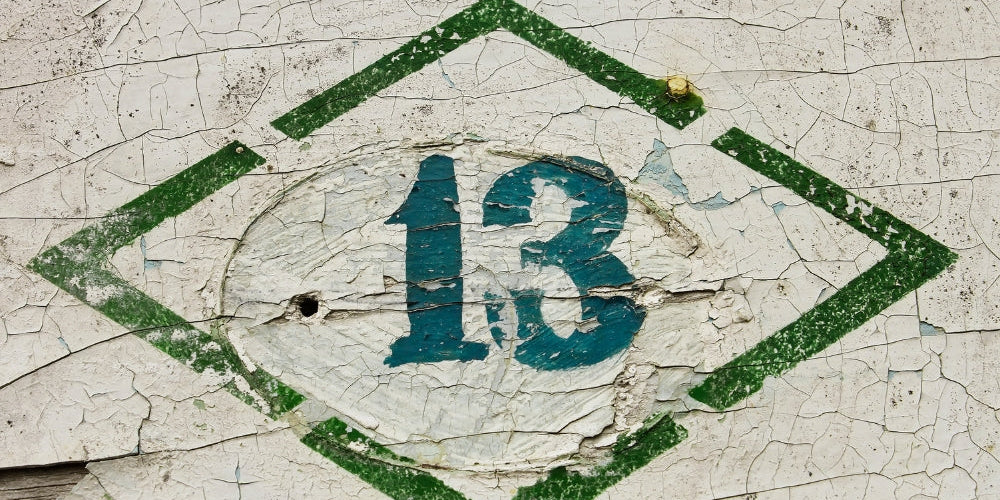 chiffre 13 peint en bleu sur mur craquelé vert et blanc symbolisant la transformation et l'heure miroir 13h13