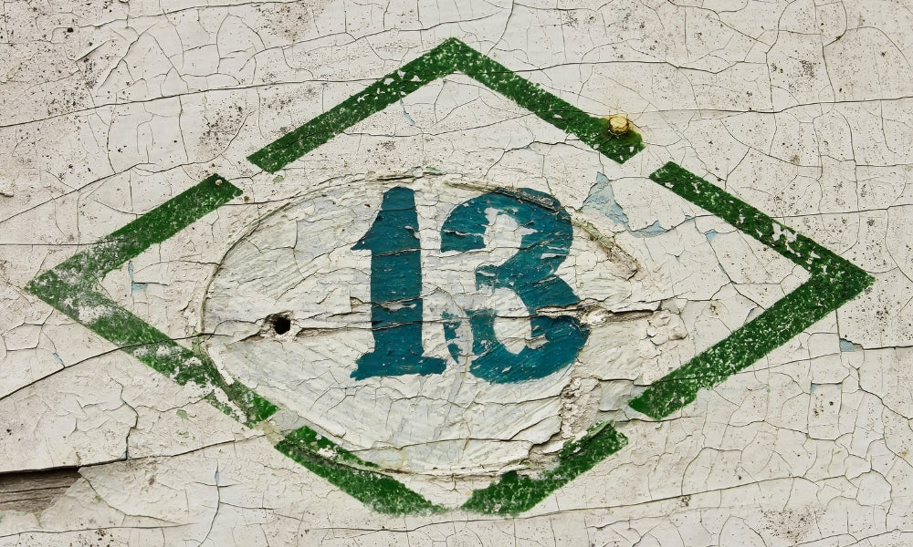 chiffre 13 peint en bleu sur mur craquelé vert et blanc symbolisant la transformation et l'heure miroir 13h13