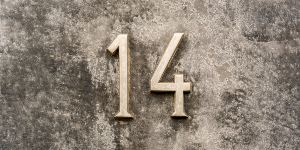 chiffre 14 doré en relief sur mur gris béton symbolisant l'heure miroir 14h14 et l'équilibre