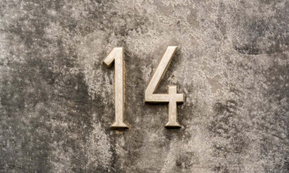 chiffre 14 doré en relief sur mur gris béton symbolisant l'heure miroir 14h14 et l'équilibre