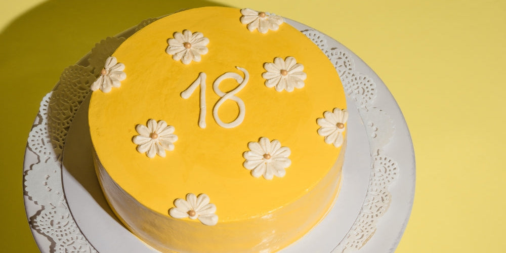 gâteau jaune avec le chiffre 18 et fleurs blanches symbolisant l'heure miroir 18h18 et la protection divine