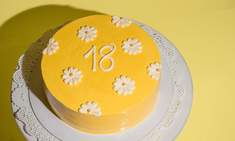 gâteau jaune avec le chiffre 18 et fleurs blanches symbolisant l'heure miroir 18h18 et la protection divine