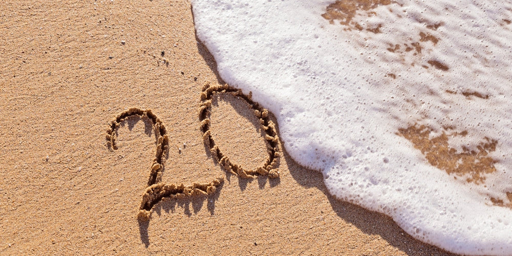 chiffre 20 écrit dans le sable sur une plage avec une vague symbolisant l'heure miroir 20h20 et le jugement