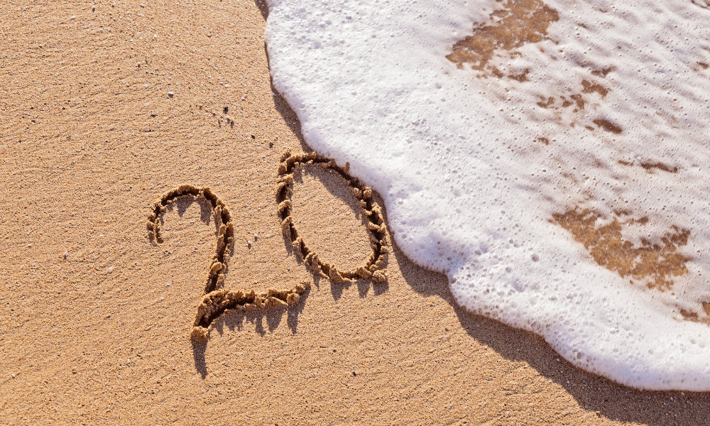 chiffre 20 écrit dans le sable sur une plage avec une vague symbolisant l'heure miroir 20h20 et le jugement