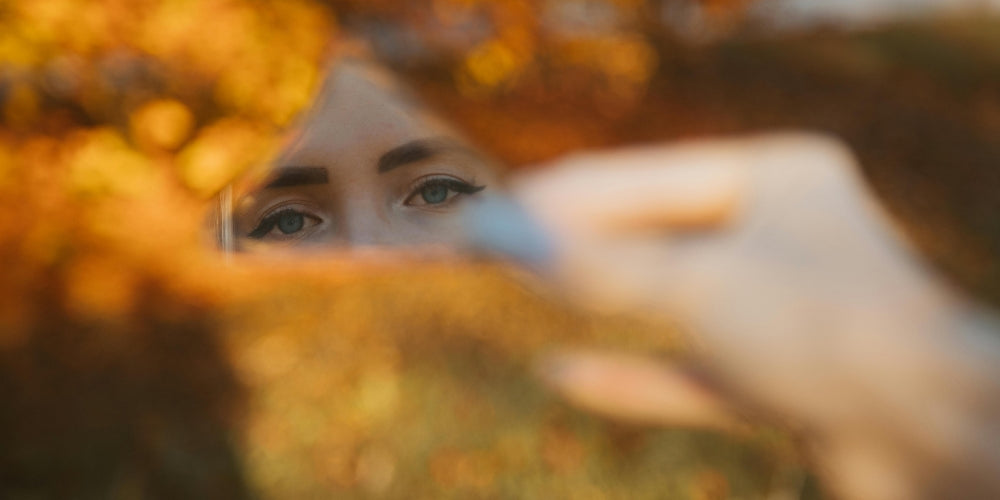 yeux de femme reflétés dans un miroir tenu à l'automne symbolisant l'éveil aux heures miroir