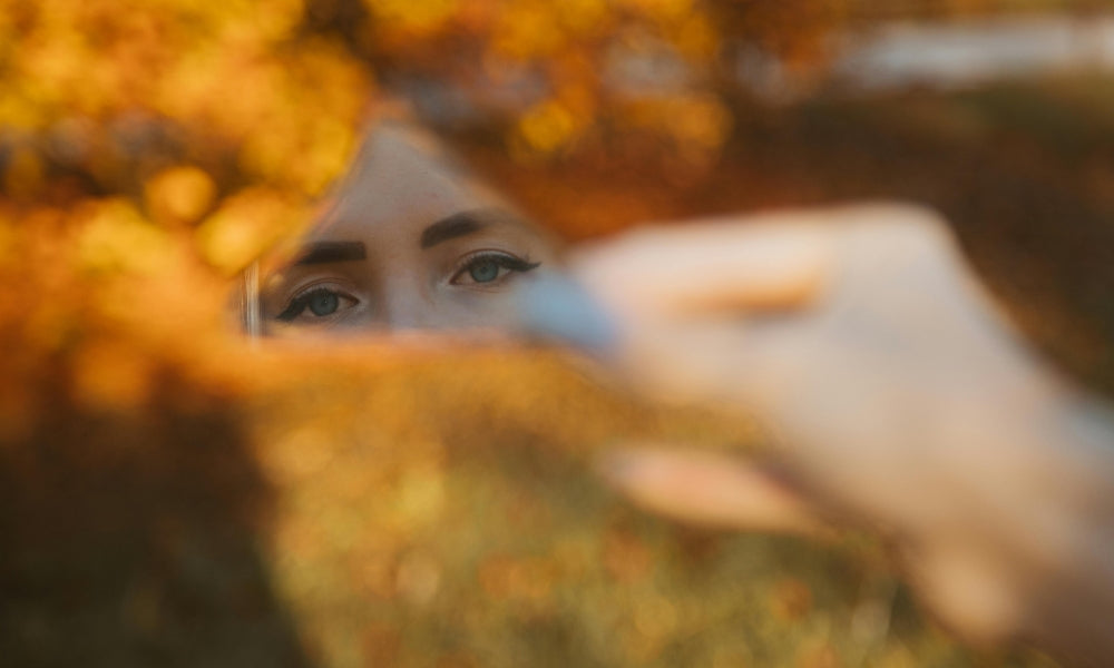 yeux de femme reflétés dans un miroir tenu à l'automne symbolisant l'éveil aux heures miroir